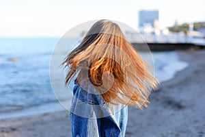 Happy young female develops hair and poses on camera, standing o