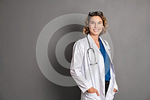 Happy young female doctor on grey wall