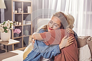 Glad girl hugging granny in room photo