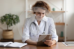 Happy young female general practitioner using digital computer tablet. photo