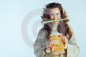 Happy young female with healthy eating book and celery