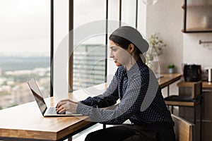 Happy young female indian employee working on computer.