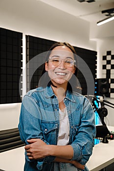 Happy young female radio host smiling while broadcasting in studio