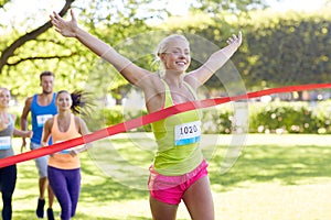 Happy young female runner winning on race finish