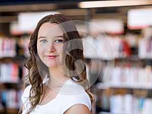 Happy female student holding books at the library