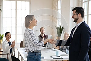 Happy young female worker shaking hands with smiling confident boss.