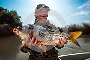 Happy young fisherman holds the big Carp fish