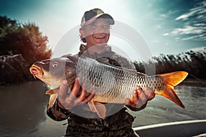 Happy young fisherman holds the big Carp fish
