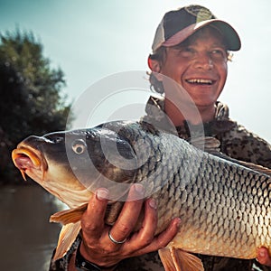 Happy young fisherman holds the big Carp fish