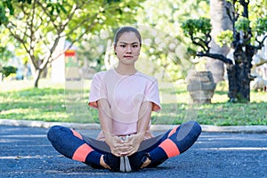 Happy young fitness woman doing stretch exercise outdoors in park