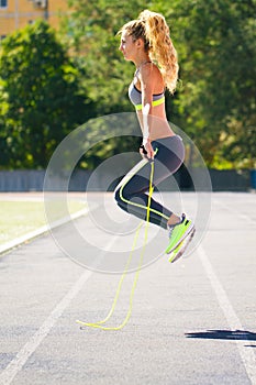 Happy Young fitness woman jumping rope at stadium