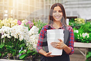 Happy young florist working in a hothouse