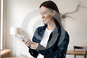 Happy young freelance business woman in casual typing on smartphone