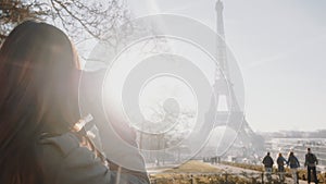 Happy young freelance photographer woman walking, taking a picture of Eiffel Tower in Paris on holiday trip slow motion.