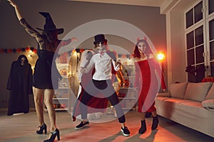 Happy young friends dancing and having fun together at festive party on Halloween night