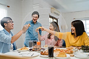 Happy young friends group having lunch at home. Asia family party eating pizza food and laughing enjoying meal while sitting at