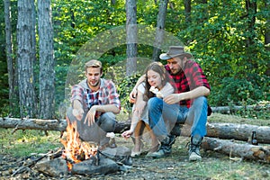 Happy young friends having picnic in the country. Company friends picnic or barbecue roasting marshmallows near bonfire.