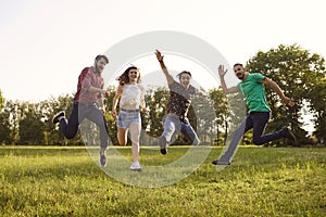 Happy young friends jumping together outdoors. Group of people having fun during summer vacation in countryside