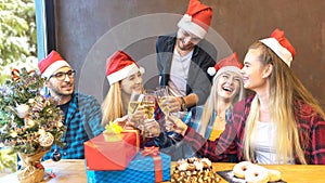 Happy young friends with santa hats celebrating Christmas with champagne and sweet food at brunch party