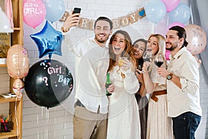 Happy young friends taking selfie together during gender reveal party