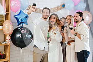 Happy young friends taking selfie together during gender reveal party photo