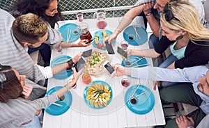 Happy young friends were sitting at a table and having a picnic outdoors