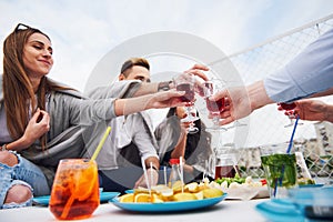 Happy young friends were sitting at a table and having a picnic outdoors