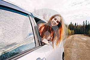 Happy young ginger woman from window car.