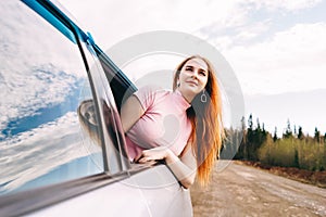 Happy young ginger woman from window car.