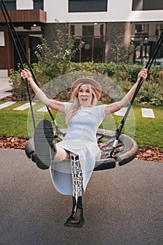 Happy young girl with bionic prosthesis swinging on a swing.