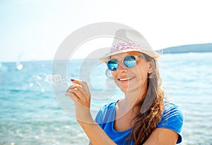 Happy young girl blowing soap bubbles on the seashore