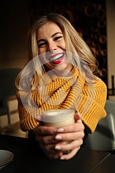 Happy young girl in cafe with glass of coffee. Positive emotions and smile