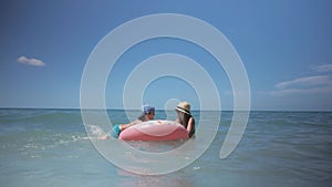 Happy young girl with child going to swim in blue sea.