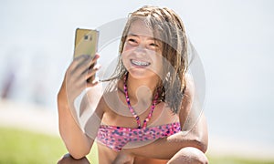 Happy young girl with dental braces making selfhie on beach in summer hot day