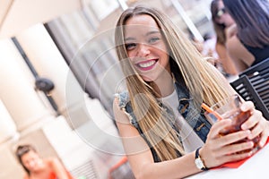 Happy young girl drinking a cocktail