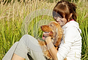 Happy young girl embracing her dog on the green gr