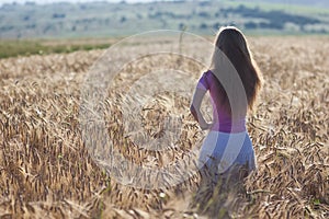 Happy young girl in golden wheat field. Young woman enjoying nat