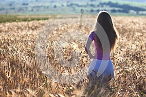 Happy young girl in golden wheat field. Young woman enjoying nat