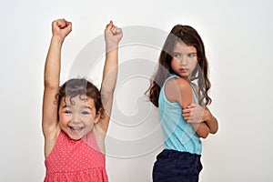 Happy young girl with hands up and her jealous older sister