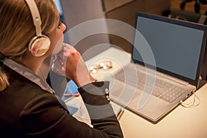 Happy young girl with headphones looking at laptop screen, reading listening online courses, studying or working remotely