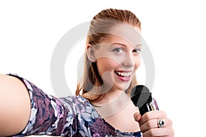 Happy young girl holding a microphone and taking a selfie