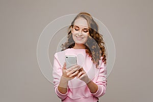 A happy young girl holding a phone looks into it and smiles