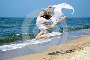 Happy young girl jumping on the beach