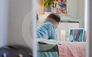 Happy young girl with laptop on bed, online dating concept.