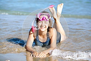 Happy young girl lies on the beach in fins and masks for scuba diving.