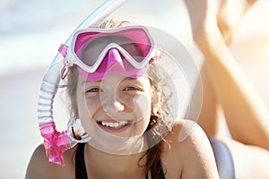 Happy young girl lies on the beach in fins and masks for scuba diving.