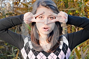 Happy young girl outdoors showing glasses sign