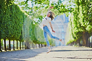 Happy young girl in Paris, jumping in Tuileries garden