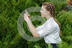 Happy young girl in park with phone in hands.