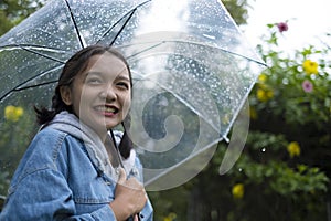 Happy young girl playing with rain in green garden